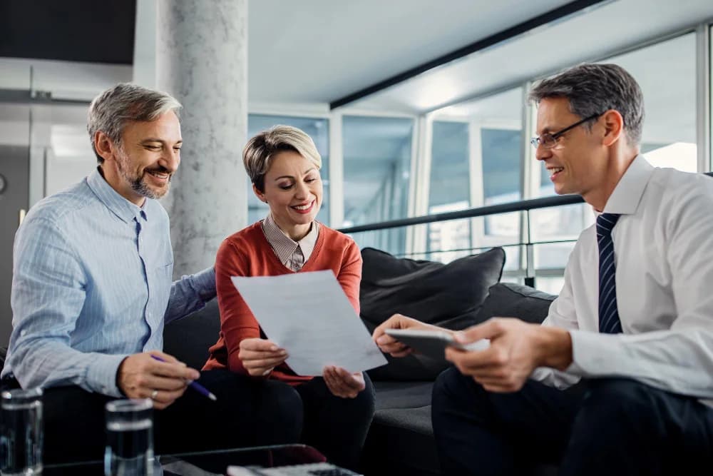 Três profissionais reunidos analisando documentos e contratos de seguro empresarial
